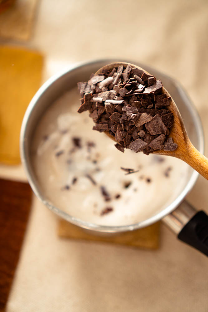 Ceremonial cacao flakes in a wooden spoon falling in a pan