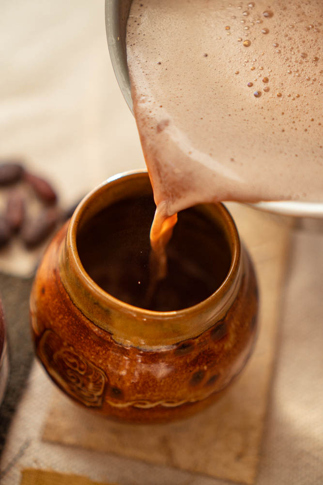 Pourring a cacao drink in a handmade cup