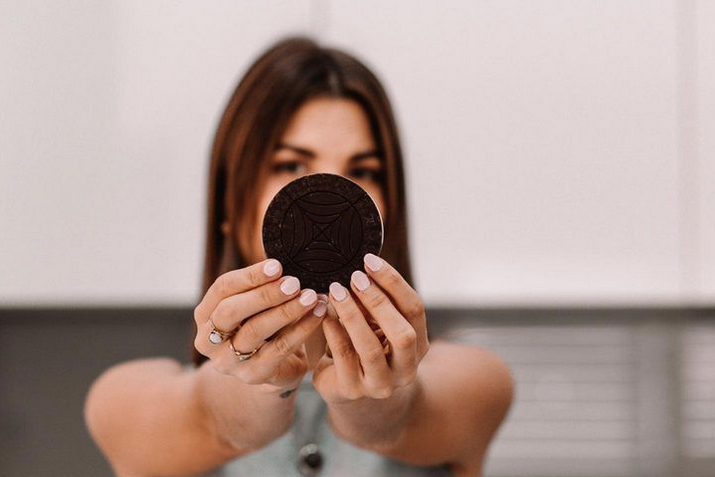 Jordan, founder of The Cacao Club, hiding behind a cacao disc